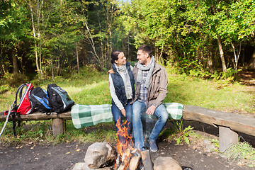 Image showing happy couple sitting on bench near camp fire