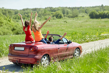 Image showing happy friends driving in cabriolet car at country