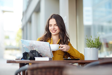 Image showing happy woman with map drinking cocoa at city cafe