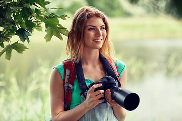 Image showing happy woman with backpack and camera outdoors