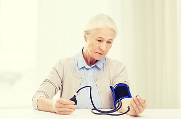 Image showing old woman with tonometer checking blood pressure