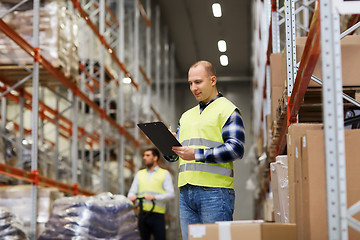 Image showing man with clipboard in safety vest at warehouse