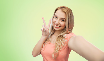 Image showing smiling woman taking selfie and showing peace sign