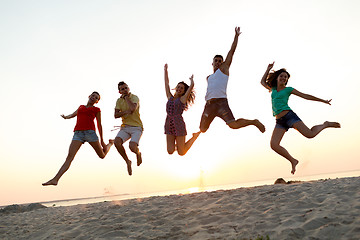 Image showing smiling friends dancing and jumping on beach