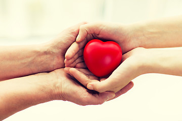 Image showing senior and young woman hands holding red heart