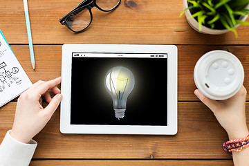 Image showing close up of woman with tablet pc on wooden table