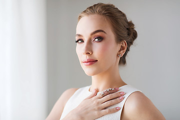 Image showing smiling woman in white dress with diamond jewelry