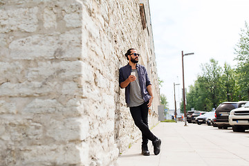 Image showing man with smartphone at stone wall on city street