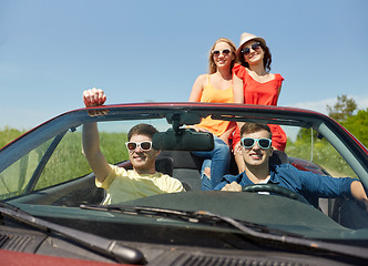 Image showing happy friends driving in cabriolet car at country