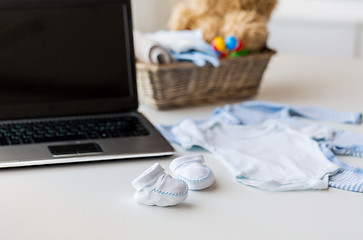 Image showing close up of baby clothes, toys and laptop at home