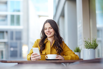 Image showing happy woman texting on smartphone at city cafe