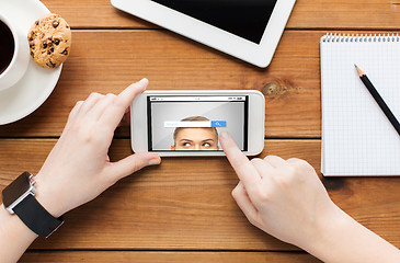 Image showing close up of woman with smartphone on wooden table