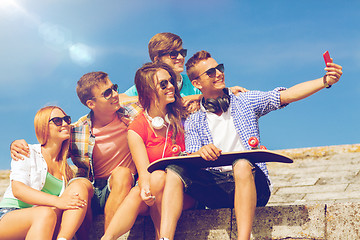 Image showing group of smiling friends with smartphone outdoors