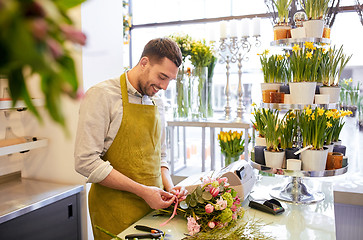 Image showing smiling florist man making bunch at flower shop