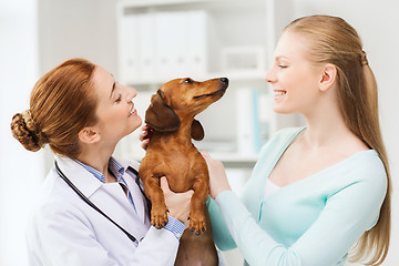 Image showing happy woman with dog and doctor at vet clinic