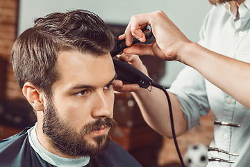 Image showing The hands of young barber making haircut  attractive man in barbershop