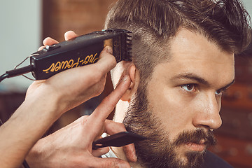 Image showing The hands of young barber making haircut to attractive man in barbershop