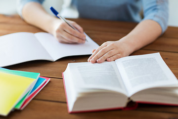 Image showing close up of student with book and notebook at home