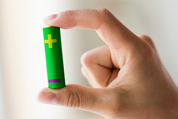 Image showing close up of hand holding green alkaline battery