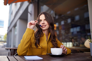 Image showing happy woman with notebook drinking cocoa at cafe