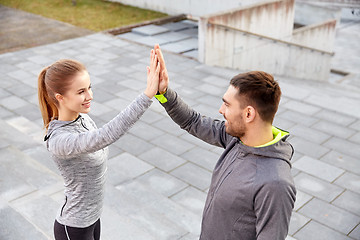 Image showing smiling couple making high five on city street