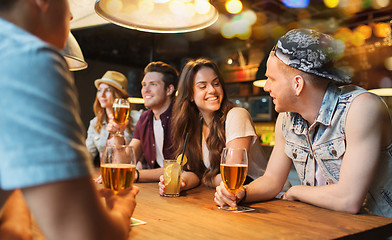 Image showing happy friends with drinks talking at bar or pub