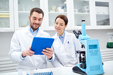 Image showing scientists with tablet pc and microscope in lab