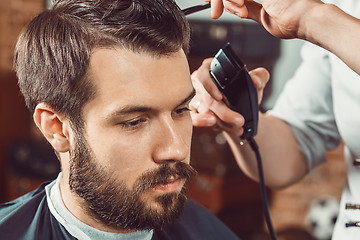 Image showing The hands of young barber making haircut  attractive man in barbershop