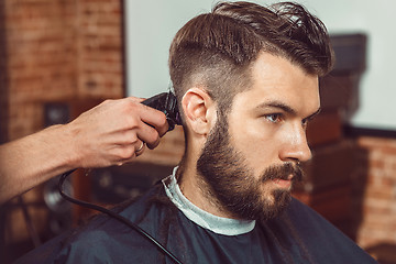 Image showing The hands of young barber making haircut to attractive man in barbershop