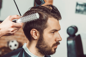 Image showing The hands of young barber making haircut attractive man in barbershop