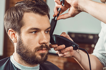 Image showing The hands of young barber making haircut attractive man in barbershop