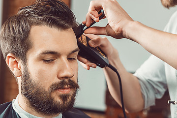 Image showing The hands of young barber making haircut  attractive man in barbershop