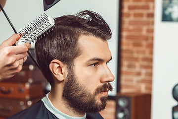 Image showing The hands of young barber making haircut attractive man in barbershop