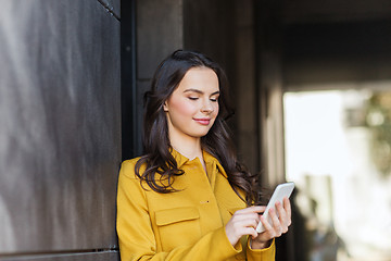 Image showing smiling young woman or girl texting on smartphone