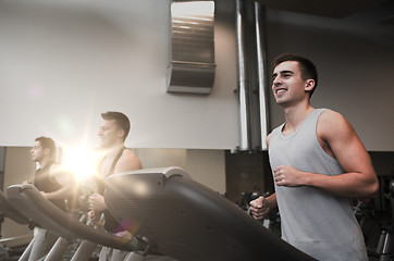 Image showing smiling men exercising on treadmill in gym