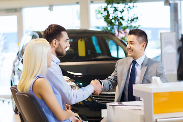 Image showing happy couple with car dealer in auto show or salon