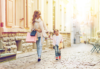 Image showing happy mother and child with shopping bags in city