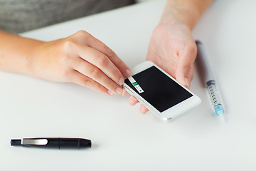 Image showing close up of woman with smartphone doing blood test