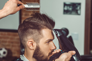 Image showing The hands of young barber making haircut to attractive man in barbershop