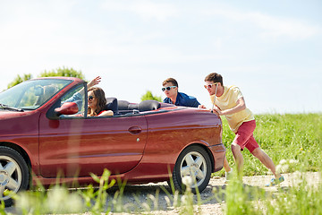 Image showing happy friends pushing broken cabriolet car