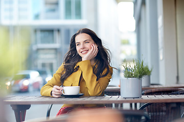 Image showing happy woman drinking cocoa at city street cafe