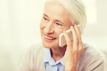 Image showing senior woman with smartphone calling at home