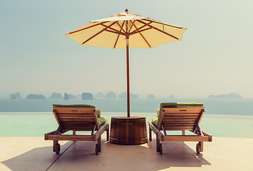 Image showing infinity pool with parasol and sun beds at seaside