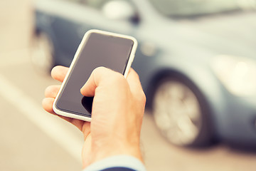 Image showing close up of man hand with smartphone and car