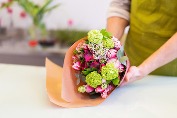 Image showing florist wrapping flowers in paper at flower shop