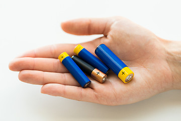 Image showing close up of hands holding alkaline batteries heap