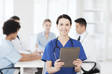 Image showing happy doctor with tablet pc over team at clinic