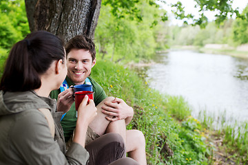 Image showing happy couple with cups drinking in nature