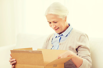 Image showing happy senior woman with parcel box at home