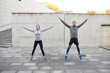 Image showing happy man and woman jumping outdoors